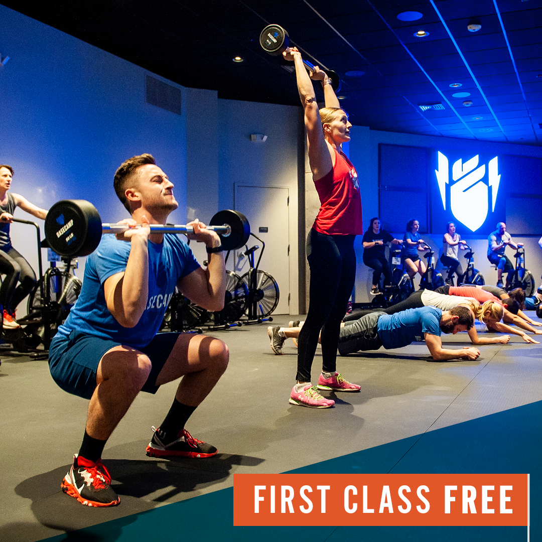 A man squatting with a barbell in a gym with a sign that says first class free