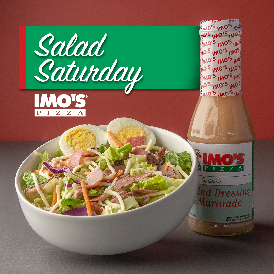 A bowl of salad next to a bottle of limo 's salad dressing