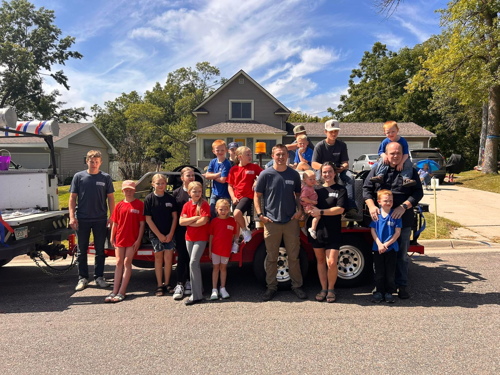 Group of people posing in front of a truck in a suburban street on a sunny day