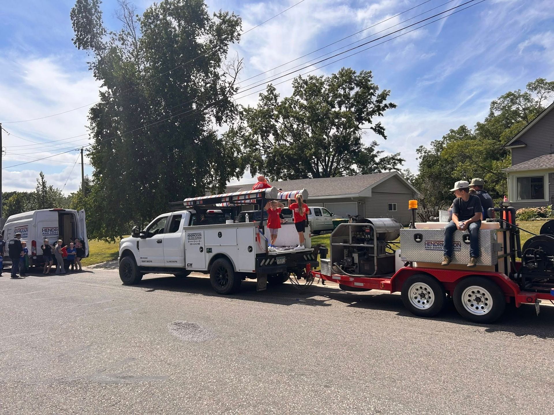 Fire truck and utility trailer parked on a suburban street with firefighters and equipment nearby.