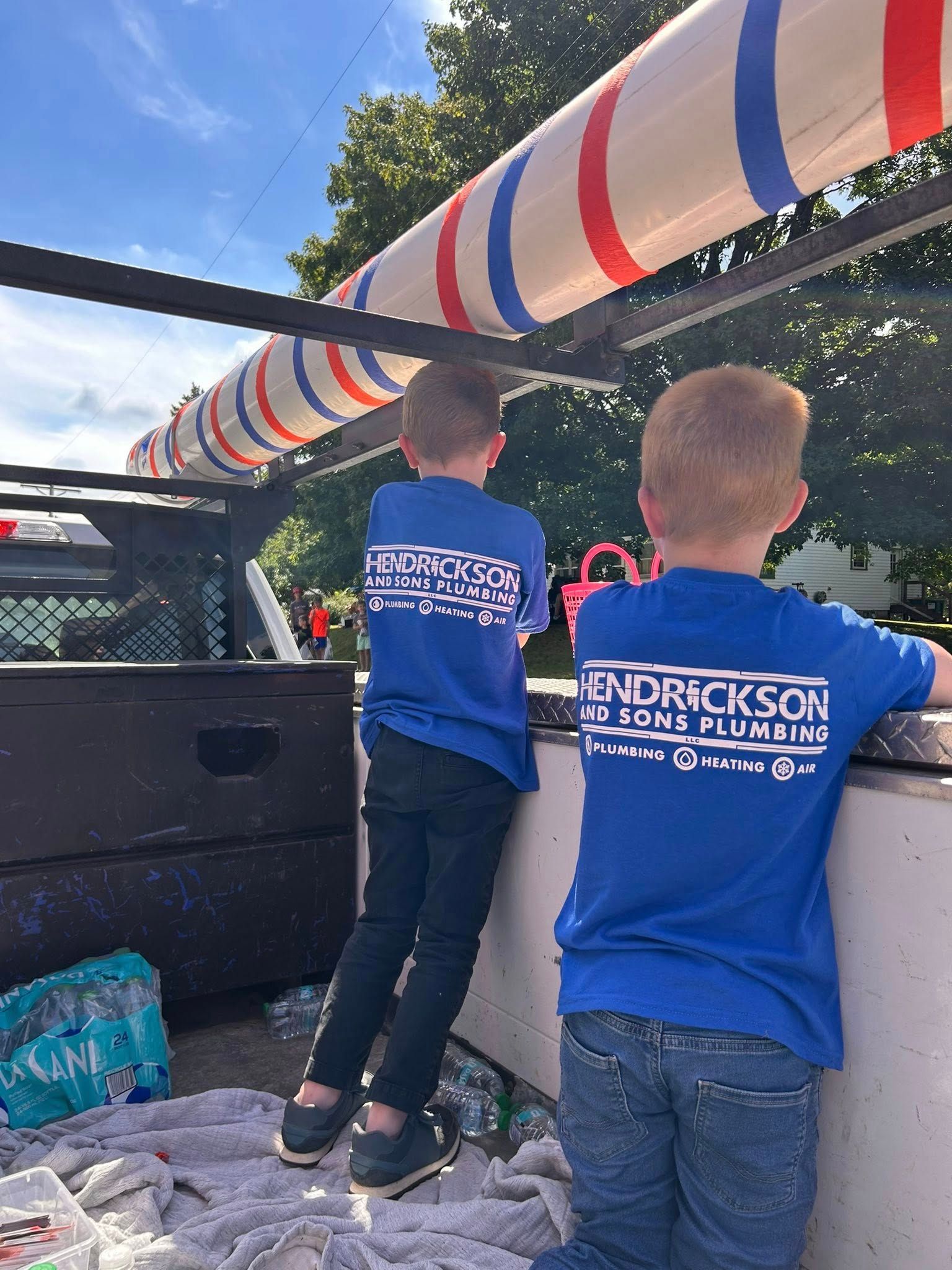 Two children in blue shirts lean over a truck bed decorated with red, white, and blue bunting.
