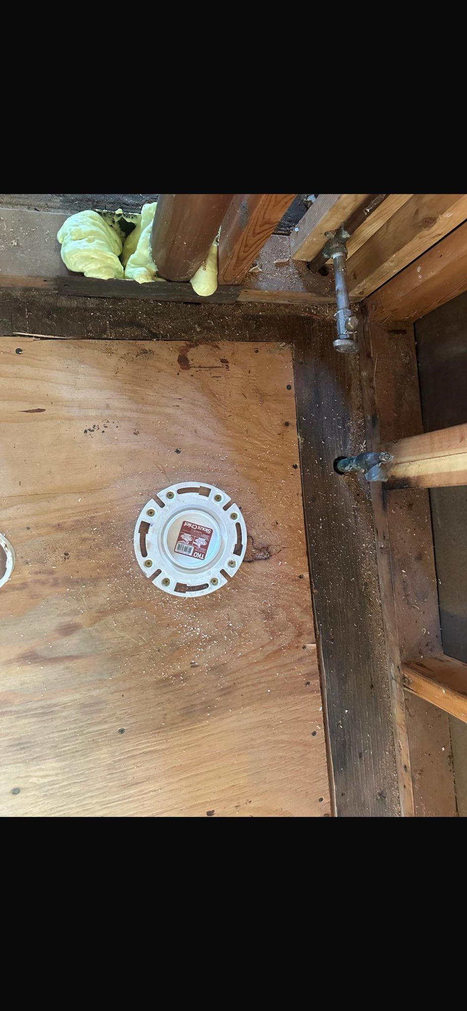 Wooden attic wall with a round white thermostat and exposed insulation near the ceiling.