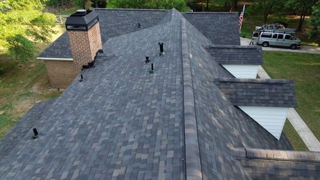 Roofers working on a terracotta-tile roof under a blue sky, with skylights visible