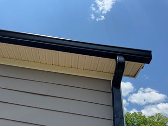 Worker repairing roof shingles with a hammer on a sloped rooftop