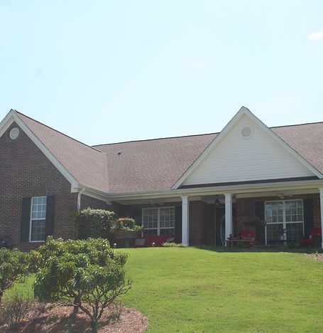 Single-story brick house with a gabled roof and a front porch on a sunny lawn.