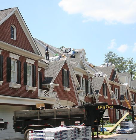 Workers repairing storm-damaged brick houses with debris and equipment on the street