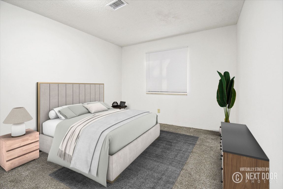 Bedroom with bed, nightstand, dresser, window with blinds, and plant.