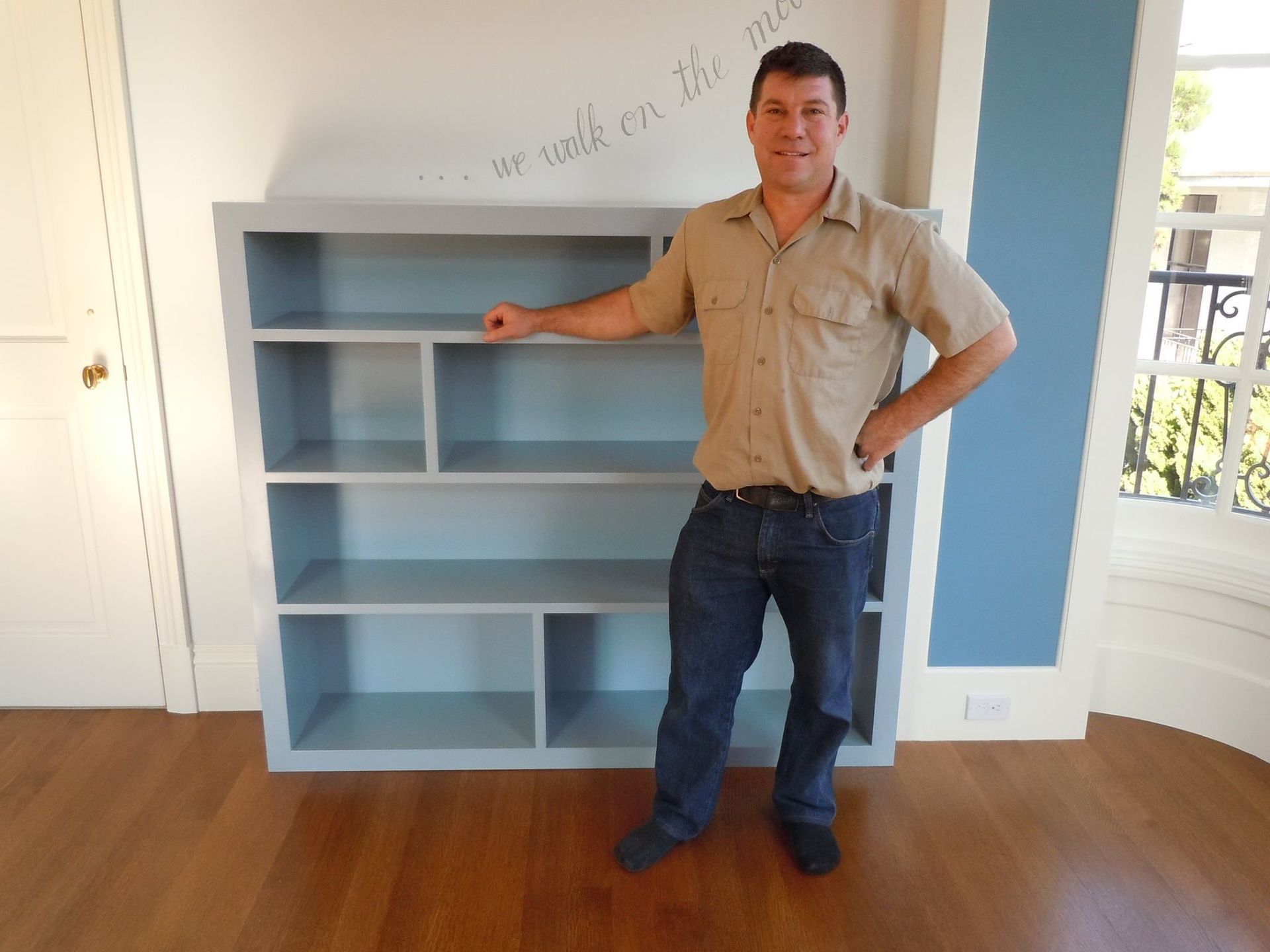 A man is standing in front of a bookshelf with the words