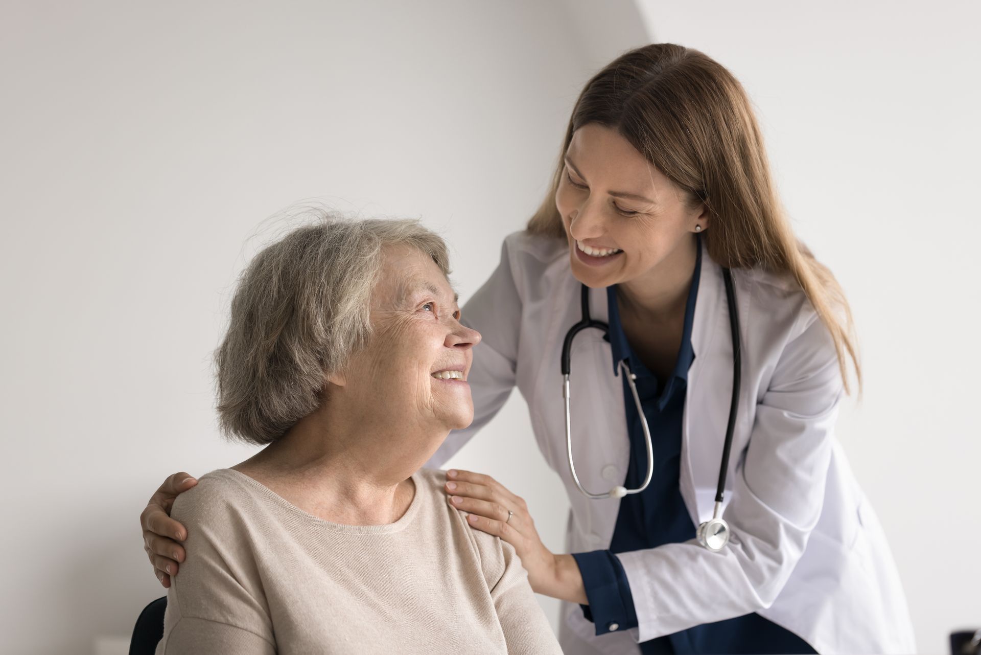 Doctor smiling and comforting an elderly patient in a bright clinic