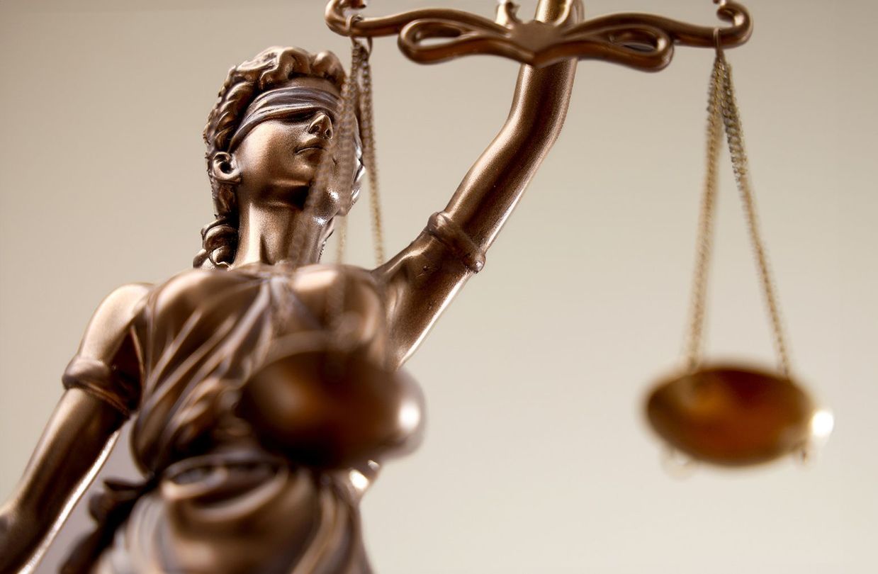 Una estatua de una dama de la justicia con los ojos vendados sosteniendo una balanza de la justicia.
