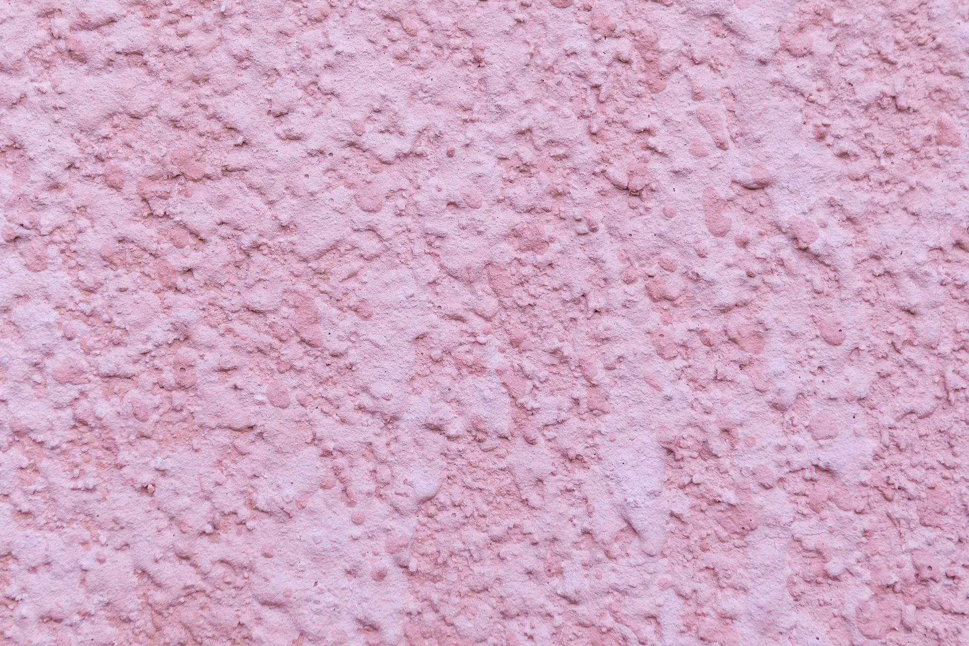 Pink textured stucco wall with a rough, speckled surface