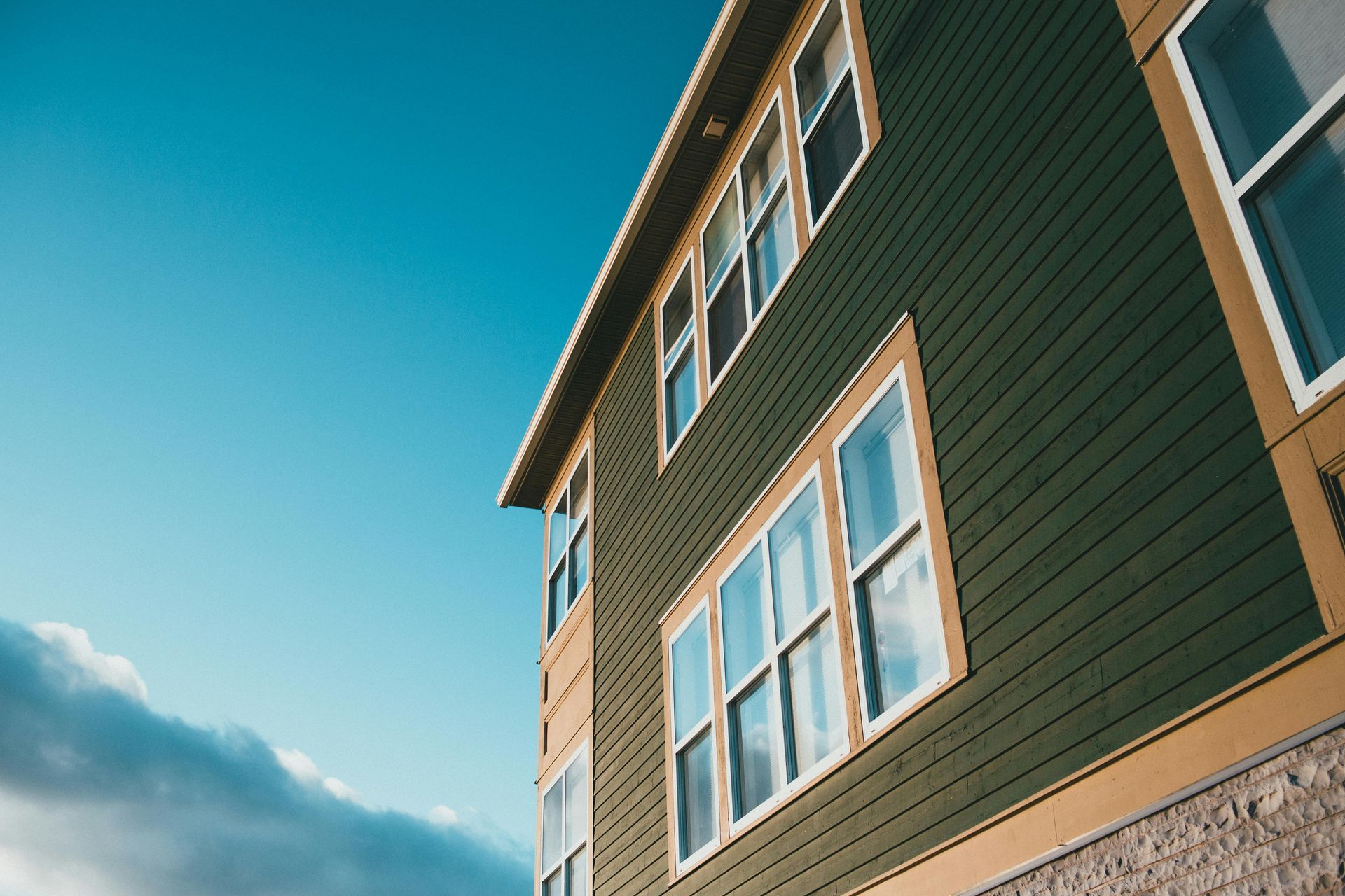Modern apartment building exterior with green siding and blue sky