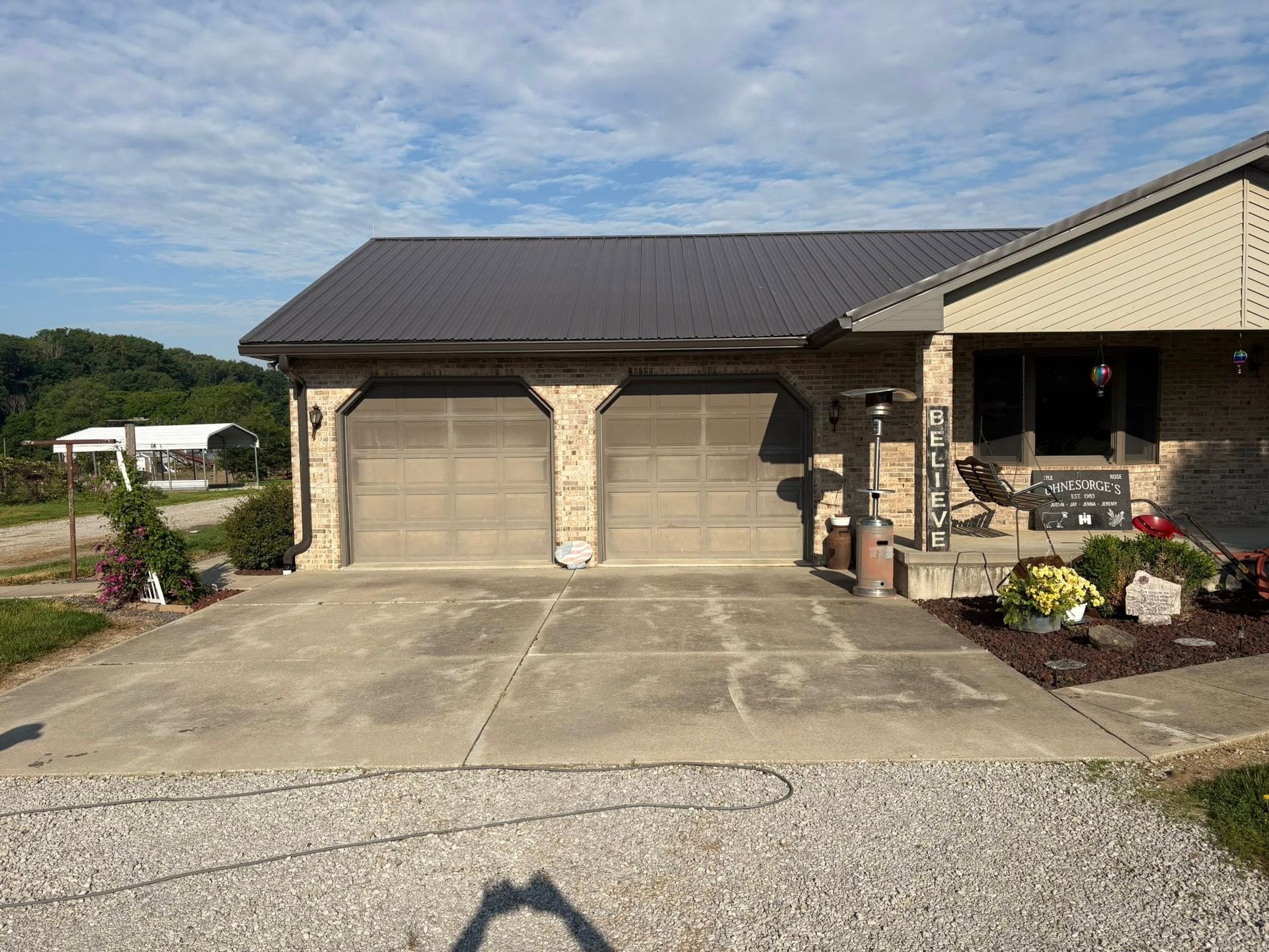 Suburban house exterior with a double garage and concrete driveway under a partly cloudy sky