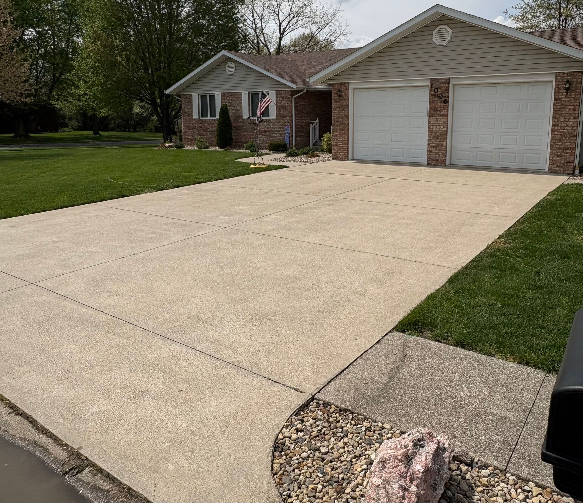 Suburban house with a double garage and wide concrete driveway, viewed from the street.
