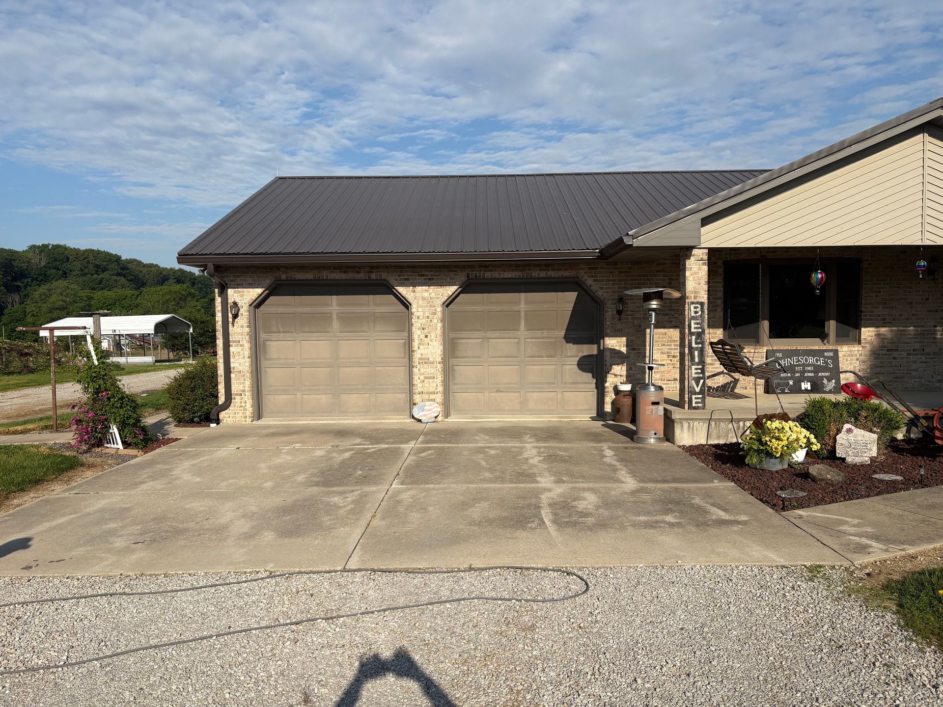 Suburban house front with a two-car garage, driveway, and landscaping under a clear sky