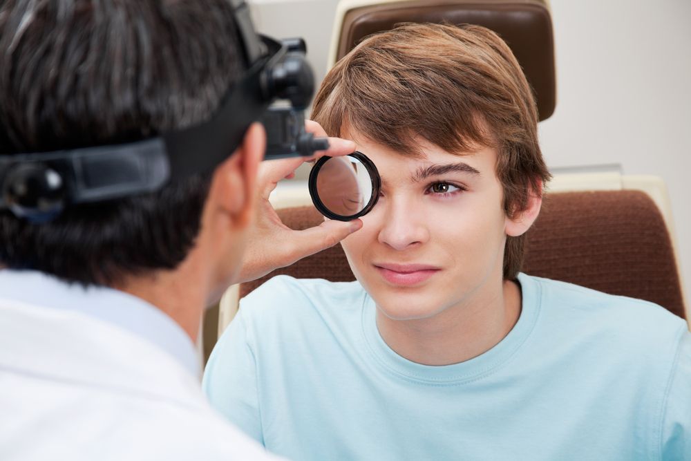 Optometrist Examining a Patient's Eye With a Lens in a Clinical Setting — EyeMax EyeCare in Newcastle, NSW