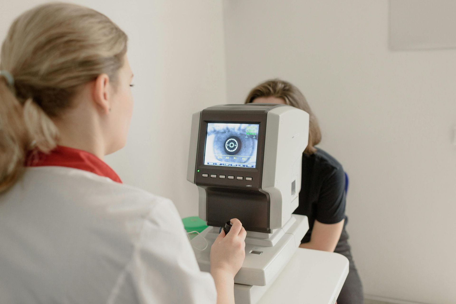 Optometrist Examining a Patient's Eye With Specialized Equipment in a White Room — EyeMax EyeCare in Wallsend, NSW