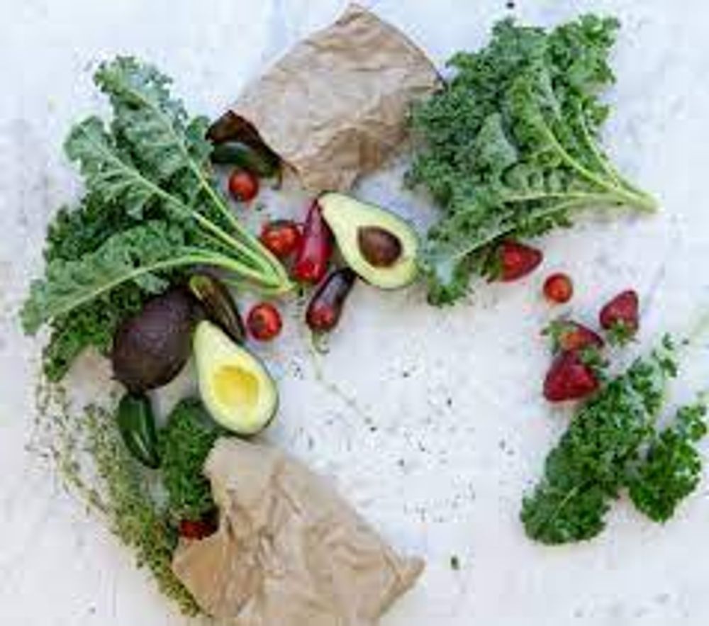 A variety of vegetables and fruits are arranged in a circle on a table.