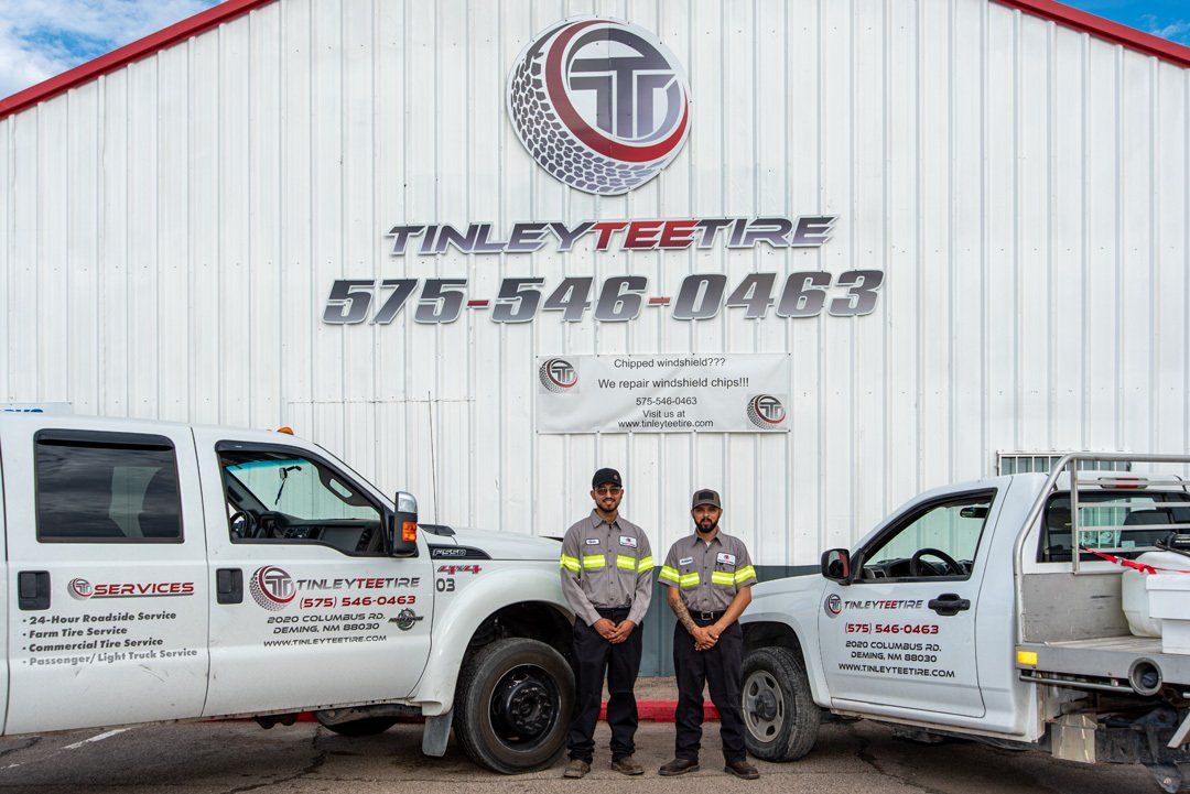 Two utility trucks and two workers standing in front of a Finney’s Towing building