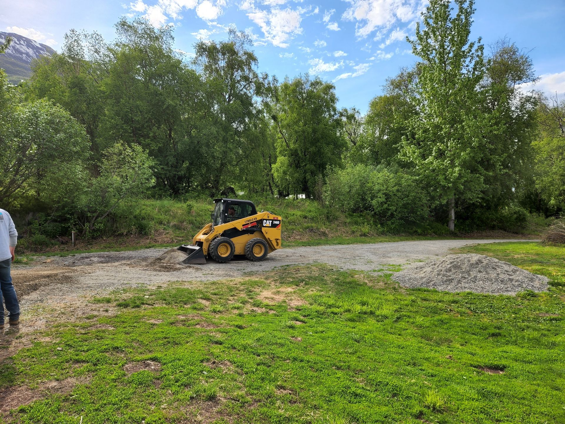 Construction vehicles digging and hauling dirt at a muddy roadside work site