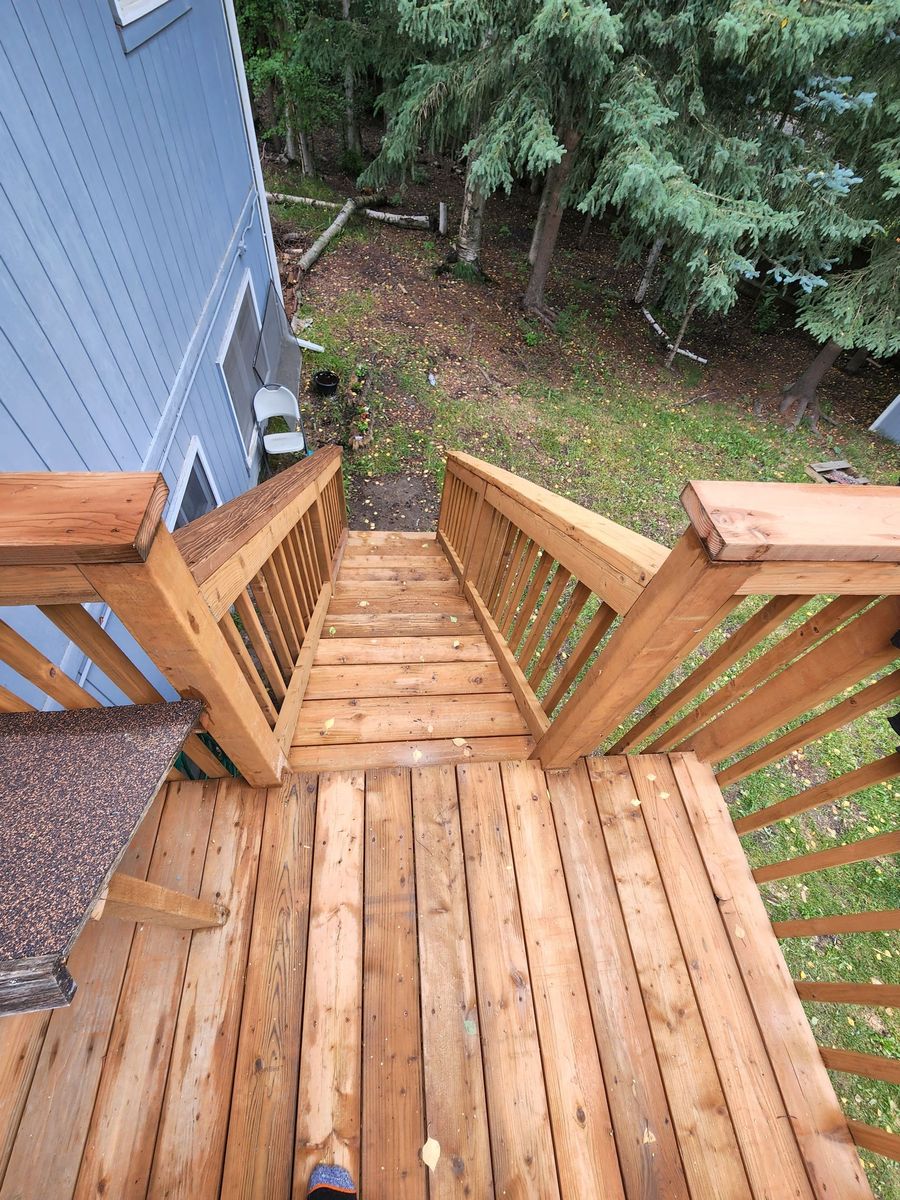 Wooden ramp leading to a house porch in a grassy yard, beside beige siding and a window.