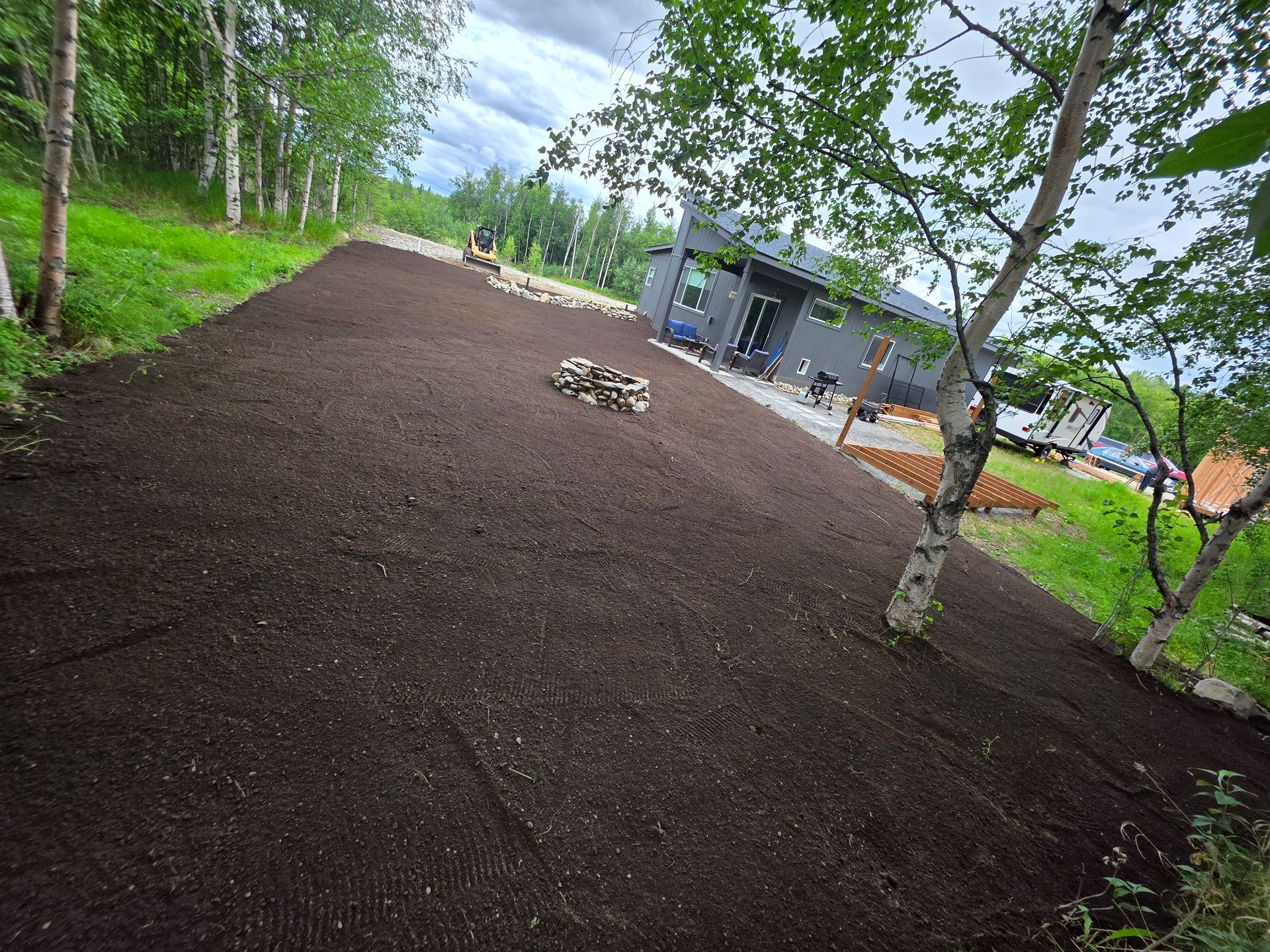 Freshly mulched yard with young trees and a house in the background
