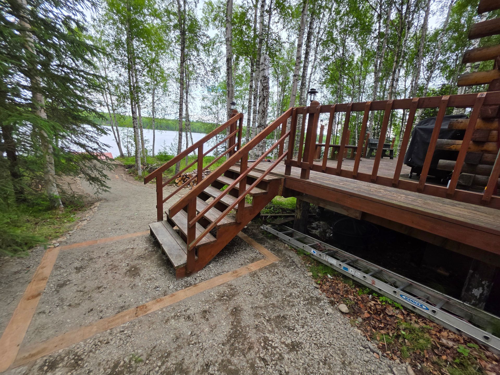 Wooden stairs and deck beside a gravel path in a forested park setting
