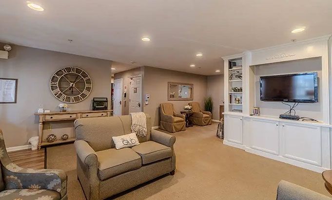 Cozy beige living room with sofa, armchair, wall clock, and built-in TV cabinet