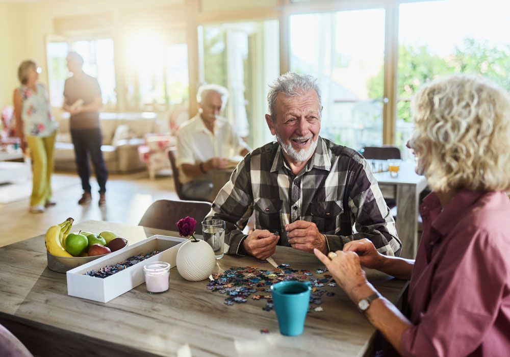 People chatting at a sunlit table in a community dining room
