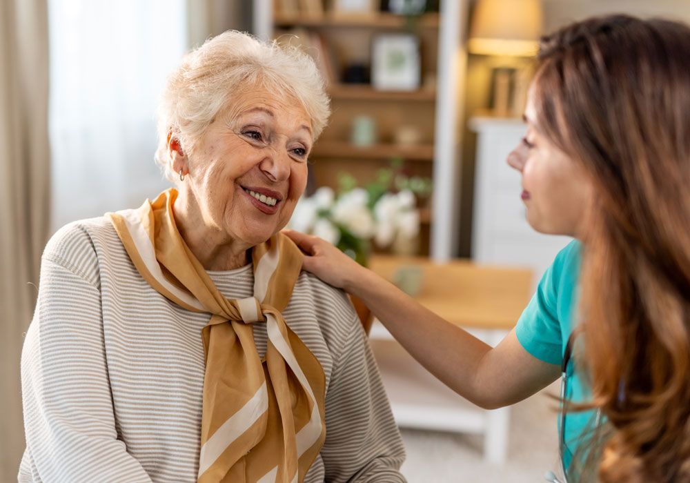 Two people talking at home, one gently touching the other’s shoulder.