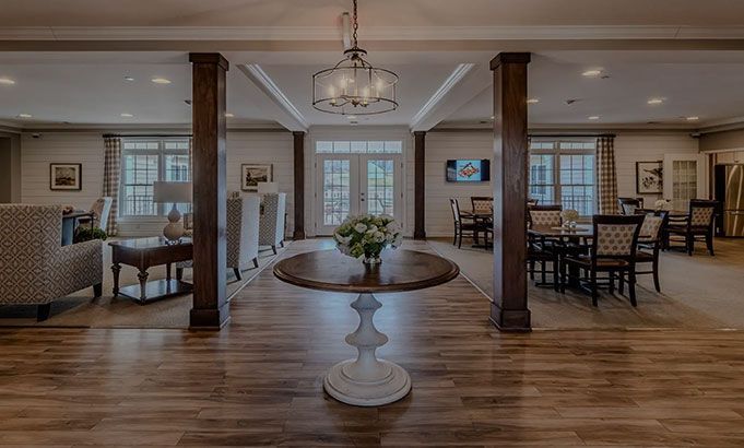 Elegant living room with hardwood floors, chandelier, columns, and seating area around a round table
