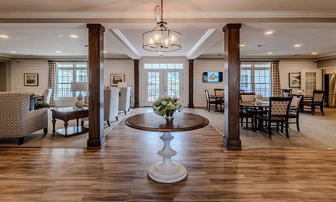 Bright formal dining room with wood floors, white pedestal table, chandelier, and seating areas at the sides
