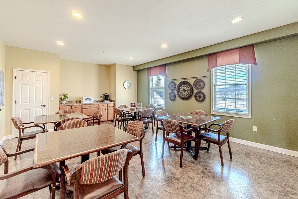 Bright dining area with tables, wooden chairs, and large windows letting in natural light.