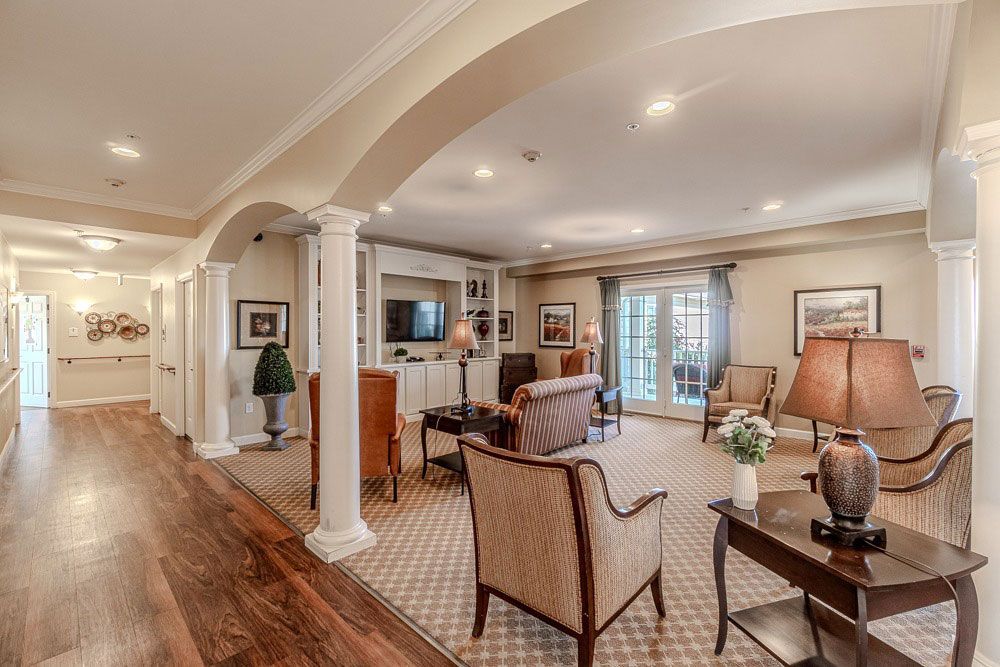 Elegant living room with arched ceiling, wood floors, and beige armchairs near sliding glass doors