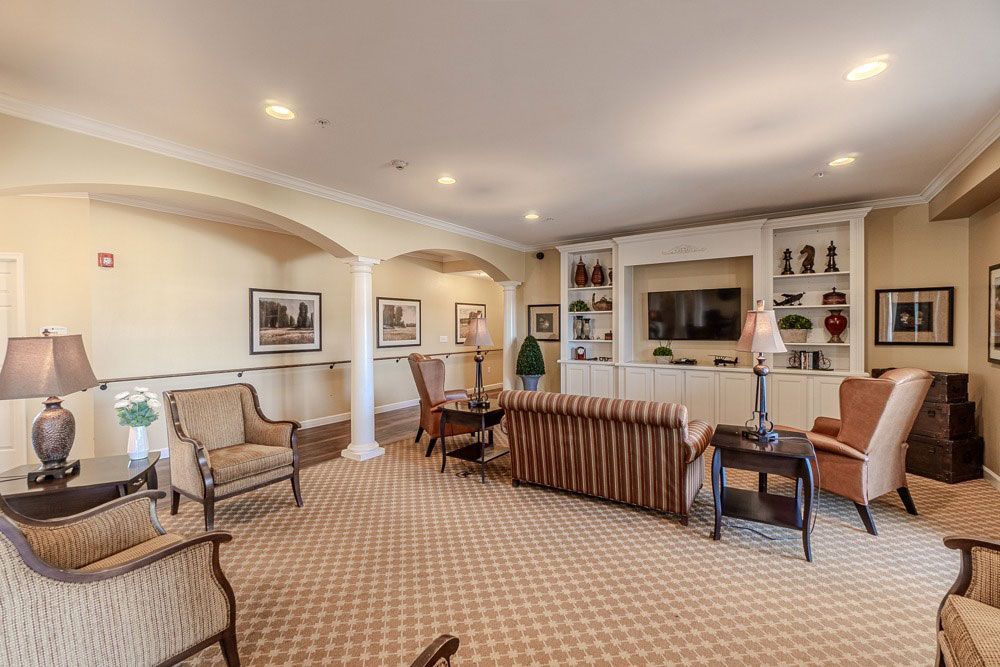 Bright living room with beige carpet, striped sofa, armchairs, a desk, and built-in shelves around a fireplace.