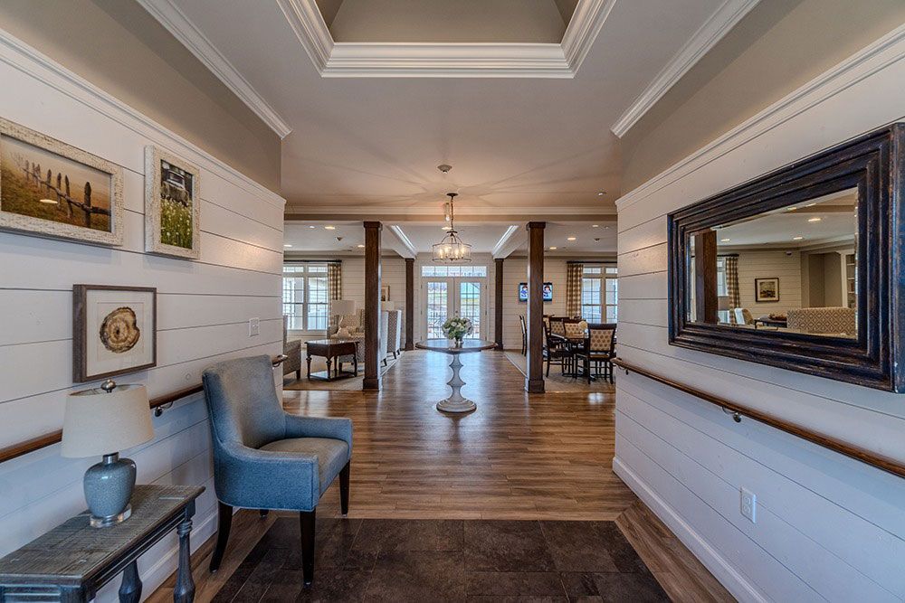 Elegant hallway with hardwood floors, blue chairs, large mirror, and French doors in a bright home interior