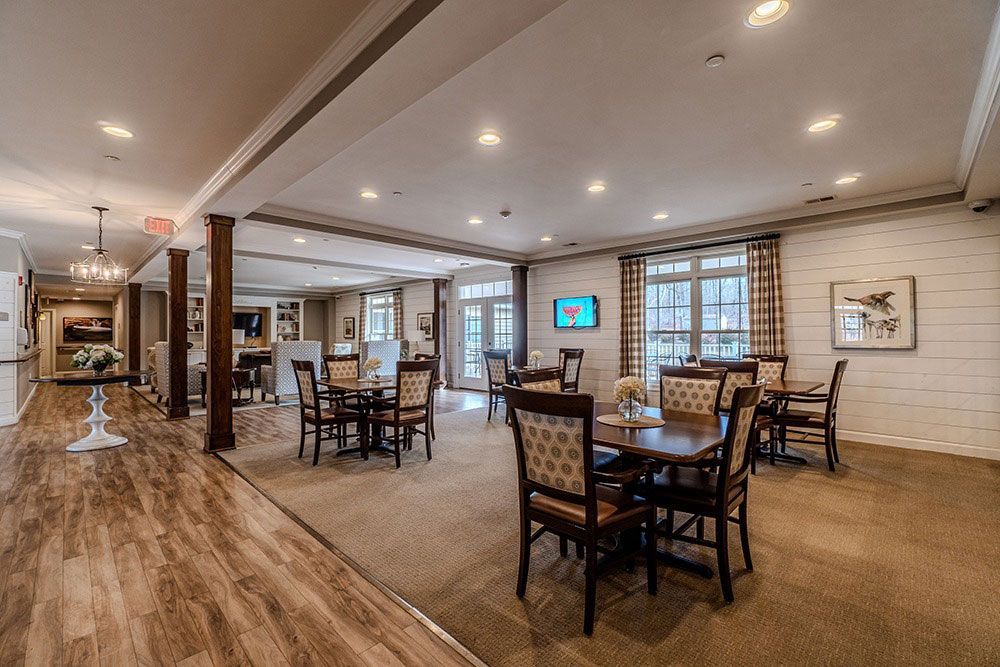Spacious restaurant dining room with wooden tables, chairs, brick walls, and bright windows
