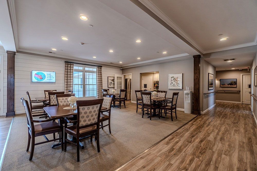 Spacious modern dining area with tables, chairs, recessed lighting, and wood flooring in an open-plan room