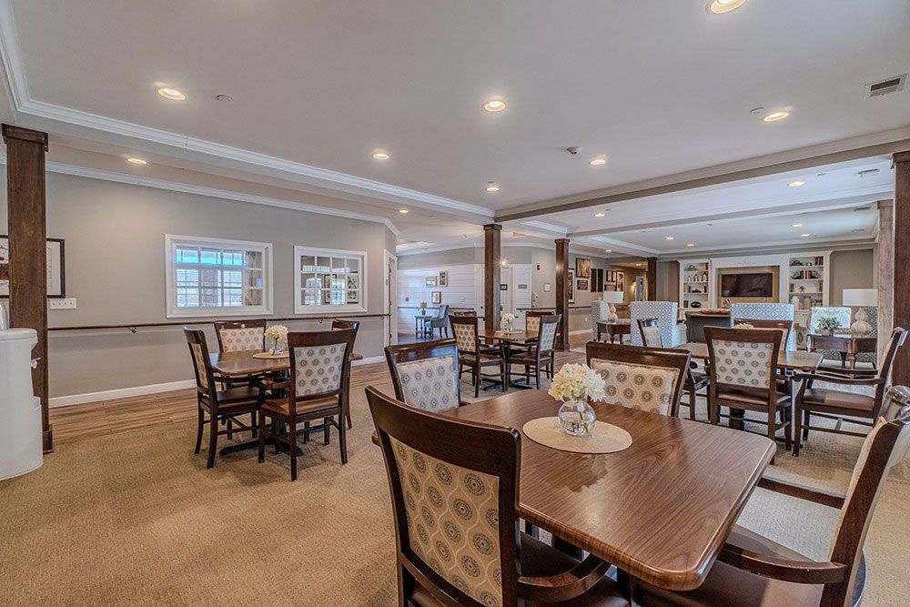 Spacious dining room with wooden tables, chairs, and soft lighting in a care facility