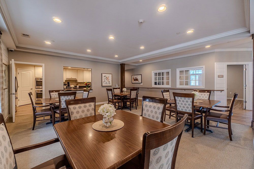 Elegant dining room with wooden tables, upholstered chairs, and recessed ceiling lights