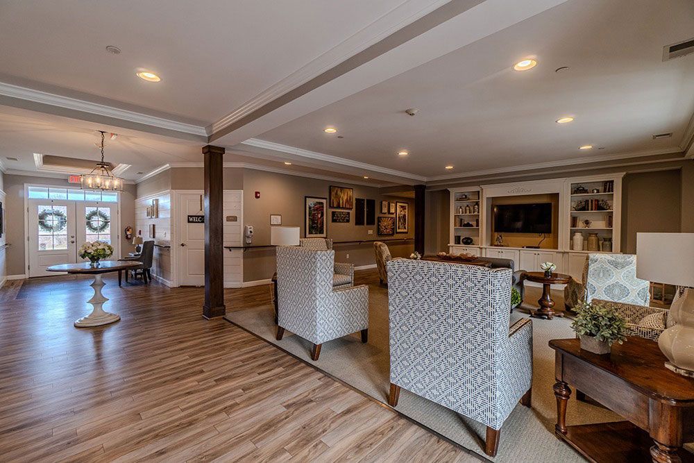 Spacious modern lobby with patterned chairs, wood floors, recessed lighting, and a front entrance.