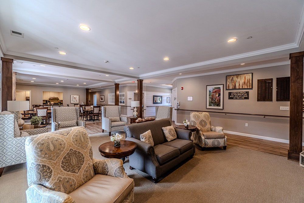 Spacious modern living room with gray sofa, patterned armchair, and open kitchen in the background