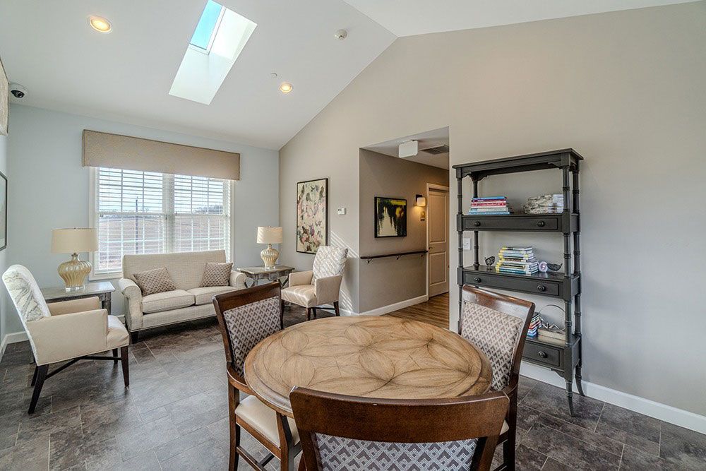 Bright living room with skylight, beige sofa, round table, and black shelving unit