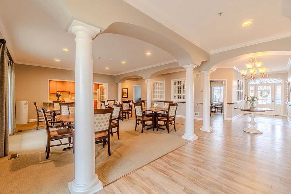 Bright open dining room with white columns, wood floors, arched ceiling, and tables and chairs.