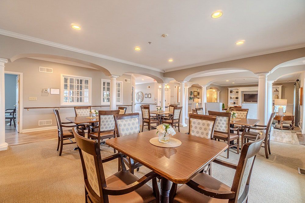 Bright, elegant dining room with wooden tables, chairs, arches, and recessed ceiling lights