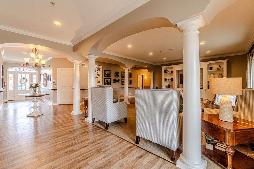 Bright open living room with white columns, wood floors, and a chandelier in a luxury home