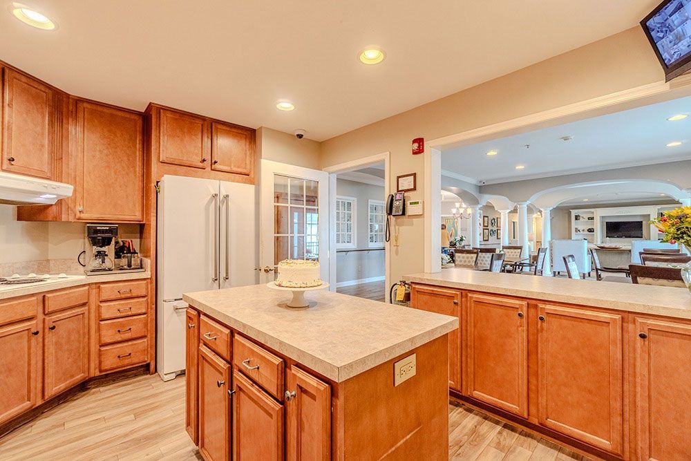 Bright kitchen with wood cabinets, white appliances, and a center island under recessed lights.