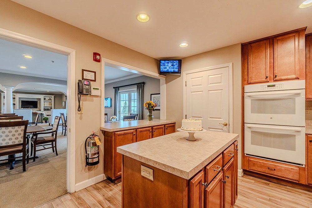 Bright kitchen with island, wood cabinets, white appliances, and a view into a dining area