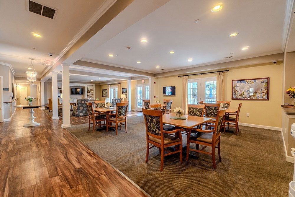 Spacious dining room with wooden tables, chairs, carpeted floor, and bright ceiling lights