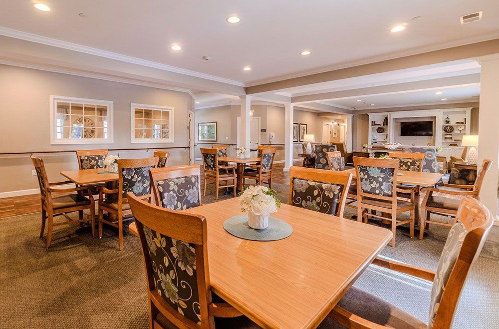 Spacious dining room with wooden tables, chairs, and warm overhead lighting